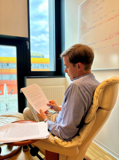 [Translate to English:] Foto von Florian Szücs beim Lesen in seinem Büro